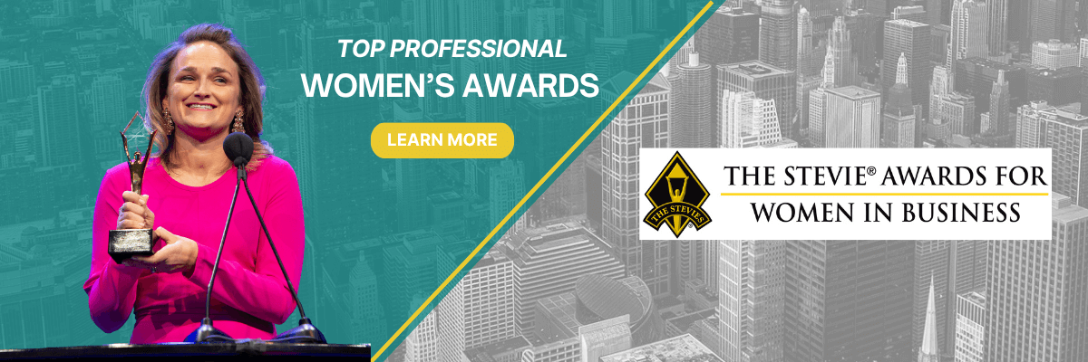 A smiling woman in a red dress holds a trophy on stage at the Stevie Awards for Women in Business. Text reads “Top Professional Women’s Awards” with a yellow “Learn More” button. A grayscale city skyline forms the background.